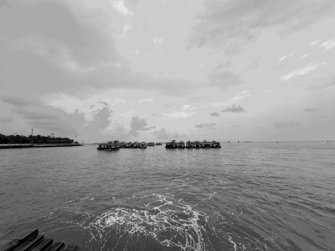 a string of boats moored just off the coast near the Gateway of India